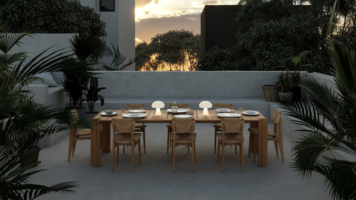 GUBI outdoor dining collection arranged in a garden at dusk