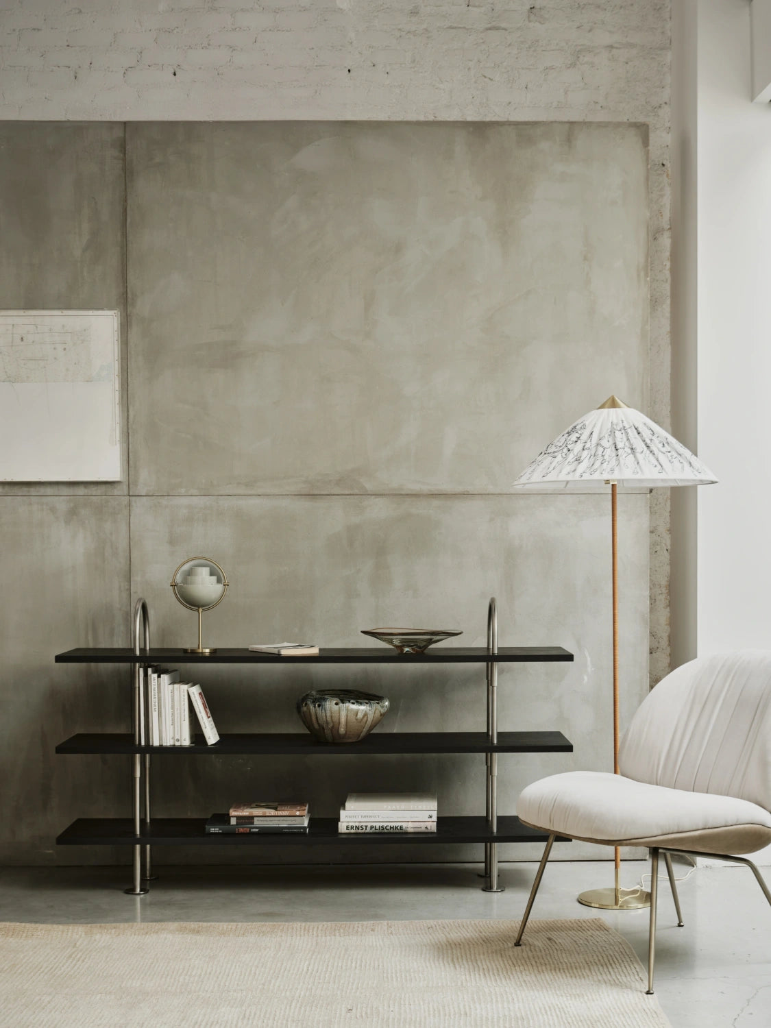 Low GUBI Keen Shelving System in satin stainless steel and black-brown ash beside a lounge chair